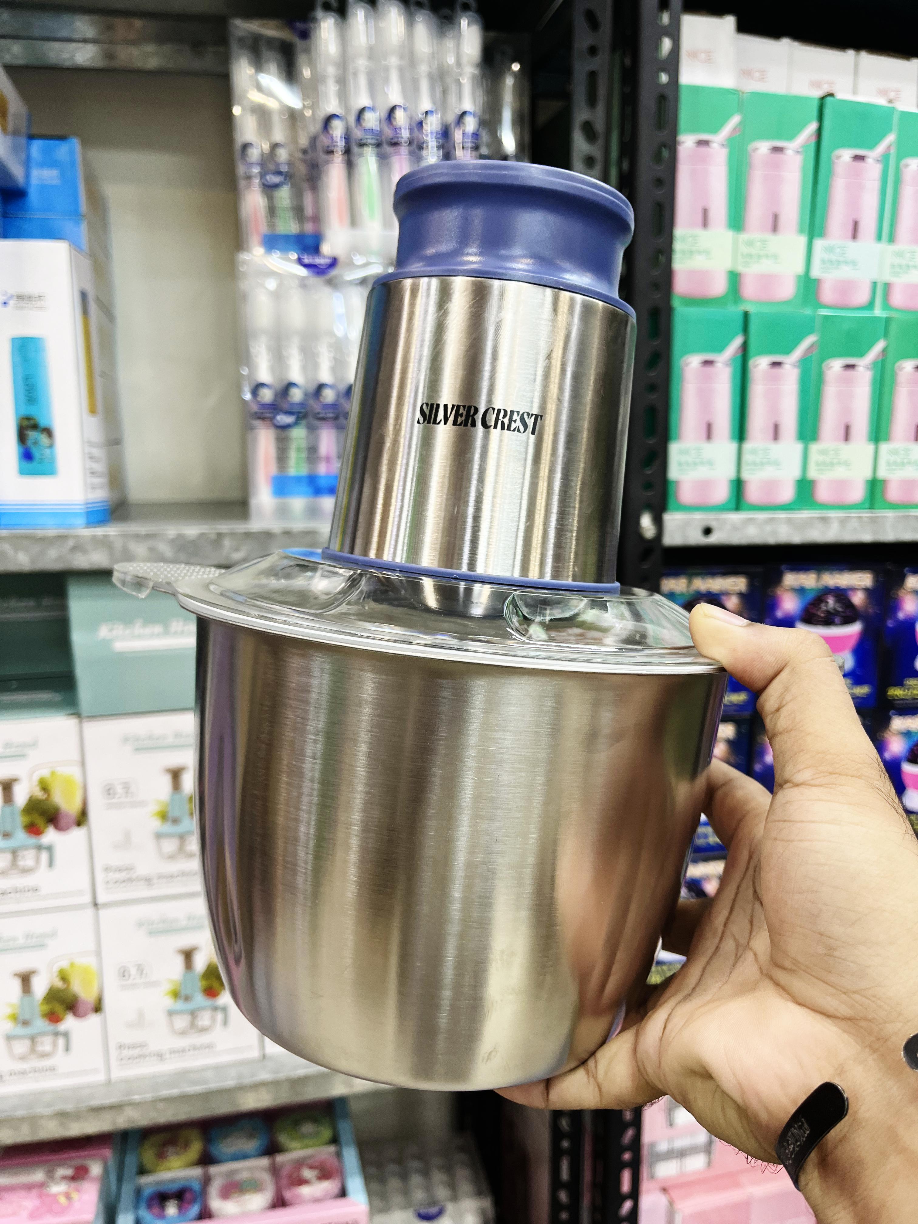Silver Crest blender held by a hand in front of a store shelf.