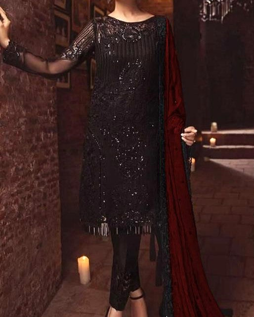 Person wearing a black sequined dress with long sleeves in a dimly lit room.