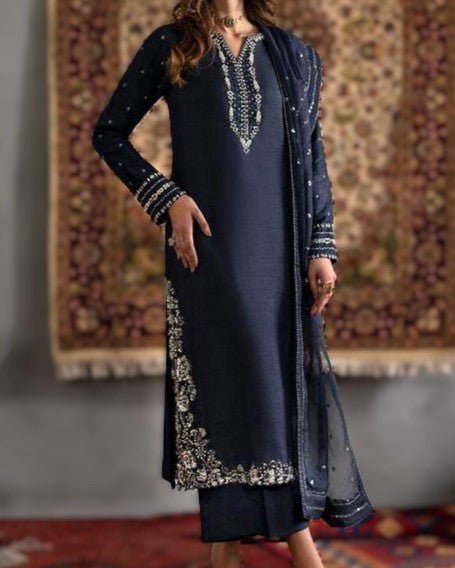 Navy blue embroidered traditional outfit with a matching dupatta against a patterned rug background