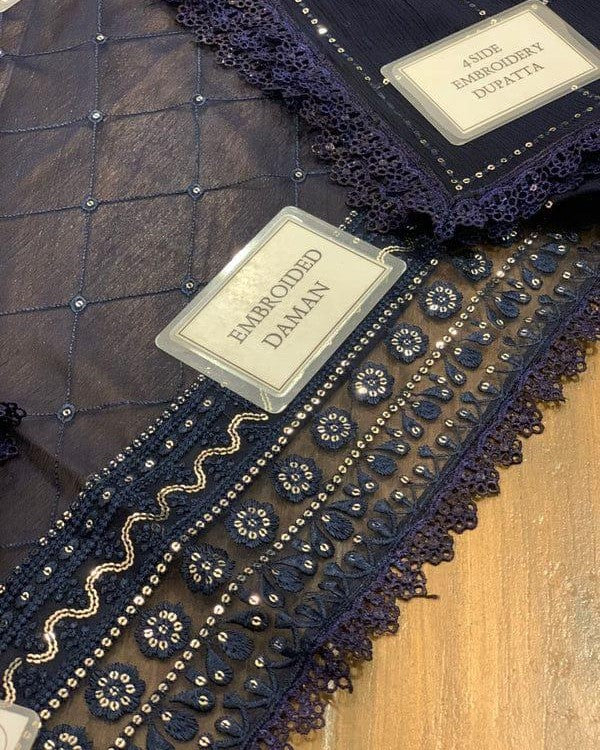 Close-up of embroidered fabric with a label indicating 'Embroidered Daman' on a wooden surface.
