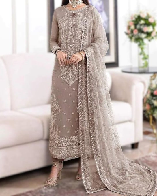Woman wearing a beige embroidered traditional outfit in a living room setting.
