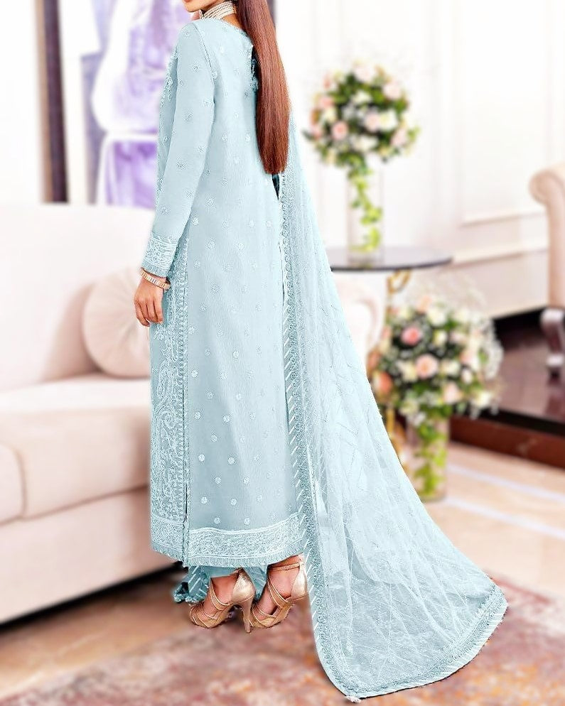 Woman wearing a light blue traditional outfit with a matching dupatta in a living room setting.
